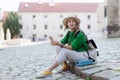 Young woman travel alone in old city centre, sitting and using smartphone. Royalty Free Stock Photo