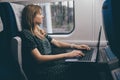 Young woman travel in train. Look at window. Using her computer. Typing on keyboard. Sit alone inside. Trip or travel Royalty Free Stock Photo