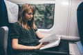 Young woman travel in train. Sit alone and read book. Concious and concentrated on process. Smart woman studying or