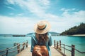 Young woman traveler with backpack and hat standing on the wooden pier and looking at sea, Rear view of a happy travel woman on Royalty Free Stock Photo