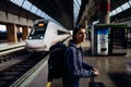 Young woman traveler with bags and suitcase waiting on the peron of a train station.Checking train times.Fast trains/metro Royalty Free Stock Photo