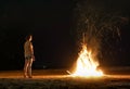 Young woman traveler feeling heat of beach bonfire with sparks