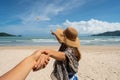 Young woman traveler holding man`s hand and looking parachute flying in the sky on the beach Royalty Free Stock Photo