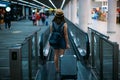 Young woman traveler in international airport with backpack holding suitcase