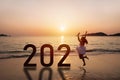 Young woman traveler jumping at the beach celebrating New Year 2021 Royalty Free Stock Photo
