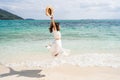 Young woman traveler jumping at beautiful tropical white sand beach with wave foam and transparent sea, Summer vacation Royalty Free Stock Photo