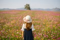 Young woman traveler looking beautiful blooming flowers field