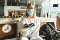 Young woman traveler in medical mask sits in the waiting room and holds out passport and ticket. Travel concept during the COVID Royalty Free Stock Photo