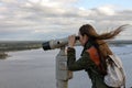 A young woman traveler on the observation deck looking through binoculars at the panorama of the city of Nizhny Novgorod Royalty Free Stock Photo