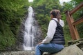 Young woman traveler observes a waterfall