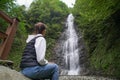 Young woman traveler observes a waterfall