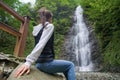 Young woman traveler observes a waterfall