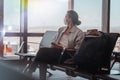 Young woman traveler in a protective medical mask with a backpack sits in the waiting room and waits for boarding a flight with Royalty Free Stock Photo