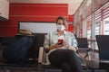 Young woman traveler in a protective medical mask with a smartphone in her hands is waiting for her flight at the airport, a new Royalty Free Stock Photo