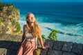 Young woman traveler in Pura Luhur Uluwatu temple, Bali, Indonesia. Amazing landscape - cliff with blue sky and sea Royalty Free Stock Photo