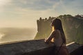 Young woman traveler in Pura Luhur Uluwatu temple, Bali, Indonesia. Amazing landscape - cliff with blue sky and sea Royalty Free Stock Photo