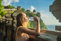 Young woman traveler in Pura Luhur Uluwatu temple, Bali, Indonesia. Amazing landscape - cliff with blue sky and sea Royalty Free Stock Photo