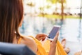 Young woman traveler relaxing and using a mobile phone by a hotel pool while traveling for summer Royalty Free Stock Photo