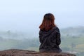 Young woman traveler sitting on mountain and looking fog in morn