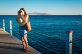 Young woman traveler taking photos of sea landscape on pier using camera. Summer fashion Royalty Free Stock Photo