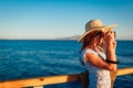 Young woman traveler taking photos of sea landscape on pier using camera. Summer fashion Royalty Free Stock Photo