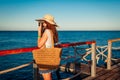 Young woman traveler taking photos of sea landscape on pier using camera. Summer fashion Royalty Free Stock Photo