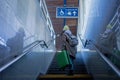 Young woman traveler tourist going up the stairs with luggage in train station. Rear view. Royalty Free Stock Photo