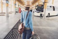 Young woman traveler waiting for a bus on a bus station, travel and active lifestyle concept