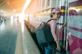 Young woman traveler waiting for a train on a train on platform of railway station, travel and active lifestyle concept Royalty Free Stock Photo