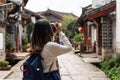 Young woman traveler walking and photographing at lijiang old town in Yunnan province Royalty Free Stock Photo