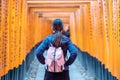 Young woman traveling at Fushimi Inari taisha Shrine, happy asian traveler looking vibrant orange torii gates. landmark and