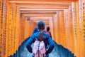 Young woman traveling at Fushimi Inari taisha Shrine, happy asian traveler looking vibrant orange torii gates. landmark and