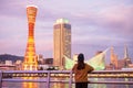 Young woman traveling at Kobe port near Osaka, Happy Asian traveler looking beautiful modern buildings at sunset. landmark and