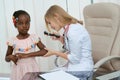 Young woman treating little girl in white dress.