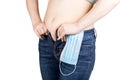 Young woman tries to button tight jeans after quarantine. Consequences of lack of activity and overeating during self-isolation