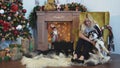 Young woman tries to put a siberian husky on the armchair by a cozy fireplace in a decorated for Christmas room