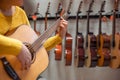 Young woman trying and buying a new wooden guitar in instrumental or musical shop, instrument concept