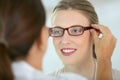 Young woman trying on eyeglasses at optical store