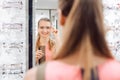 Young woman trying fashionable glasses in optometrist store