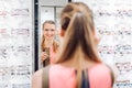 Young woman trying fashionable glasses in optometrist store