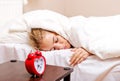 Young woman trying to sleep when alarm clock ringing