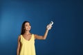 Young woman turning on air conditioner blue background