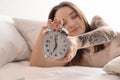 Young woman turning off alarm clock in bed. Early morning Royalty Free Stock Photo