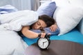 Young woman turning off alarm clock in morning. Royalty Free Stock Photo