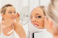 Young woman tweezing eyebrows in bathroom