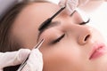 Young woman tweezing her eyebrows in beauty saloon Royalty Free Stock Photo