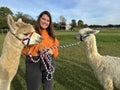 Young woman with two alpacas, a Huacaya and a Suri, outdoors