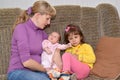 The young woman with two small children sit on a sofa