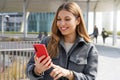 Young woman typing with her finger on her mobile phone outside the subway station Royalty Free Stock Photo