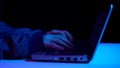 A young woman is typing on a laptop keyboard. Hands close up. Hacker makes a hack through a laptop. Blue and red light Royalty Free Stock Photo